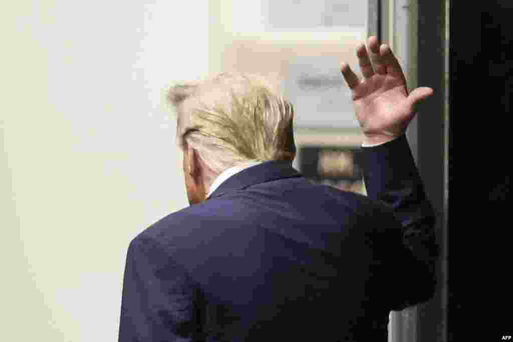 Former U.S. President Donald Trump gestures while walking in a hallway outside the courtroom as he attends his trial for allegedly covering up hush money payments linked to extramarital affairs, at Manhattan Criminal Court in New York City.