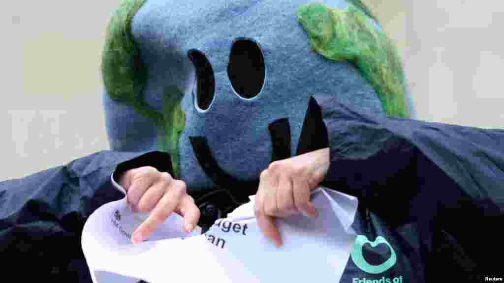 An environmental campaigner tears a piece of paper that says "Carbon budget delivery plan" outside the High Court in London. The court ruled that Britain's latest climate action plan is unlawful, in a legal challenge brought by environmental groups.