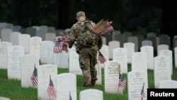 Un soldado del Ejército de EEUU coloca una bandera en una lápida durante el evento anual 'Flags In', antes del Día de los Caídos en el Cementerio Nacional de Arlington en Arlington, Virginia, el 23 de mayo de 2024.