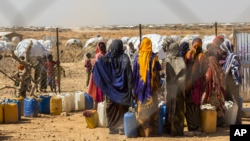 Des femmes et des enfants déplacés par la sécheresse vont chercher de l'eau dans un point de distribution proche du site de Farburo pour personnes déplacées à Gode, dans la région Somali de l'Éthiopie, le 27 janvier 2018.