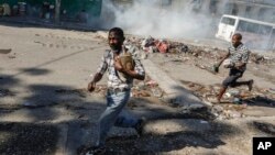 Hombres corren a refugiarse mientras la policía antidisturbios lanza gases lacrimógenos en un esfuerzo por dispersar a la gente cerca del Palacio Nacional, en Puerto Príncipe, Haití, el martes 2 de abril de 2024.[Foto: Archivo/AP].