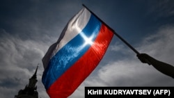 Seorang pria mengibarkan bendera nasional Rusia di pusat kota Moskow menjelang Hari Rusia pada 11 Juni 2023. (Foto: AFP/Kirill KUDRYAVTSEV)