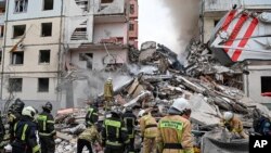 Foto yang dirilis oleh Gubernur wilayah Belgorod Vyacheslav Gladkov di media sosial pada 12 Mei 2024, menunjukkan pekerja darurat Rusia di luar blok apartemen yang sebagian runtuh setelah serangan rudal Ukraina, di kota Belgorod.