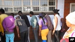 Watu wanatafuta majina yao, nje ya kituo cha kupigia kura mjini Harare, Agosti 24, 2023