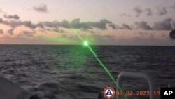 FILE - This photo provided by the Philippine Coast Guard shows a green military-grade laser light from a Chinese coast guard ship in the disputed South China Sea, Feb. 6, 2023. 