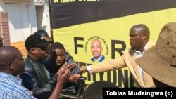 Amapholisa ahlasele isikhulumeli seCCC uMnu Promise Mkhwananzi ezama ukumbopha ngesikhathi ekhuluma lentathelizindaba ngoMgqibelo eHarare. 