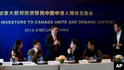 資料照：北京的一名移民諮詢人員在一個記者會上與參會者交談。（2014年3月4日）