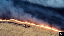 Esta fotografía publicada por el Departamento de Silvicultura y Protección contra Incendios de California muestra una excavadora trabajando contra el incendio de Corral el domingo 2 de junio de 2024, cerca de Tracy, California. 