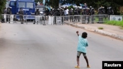 A young boy gestures at police as demonstrators gather in the streets for a third day of anti-government protests in Accra, Ghana, Sept. 23, 2023.