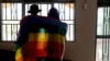 FILE - A gay Ugandan couple cover themselves with a pride flag as they pose for a photograph in Uganda, March 25, 2023.