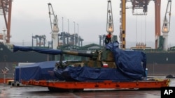 FILE - A worker uncovers a South Korean Thunder K9 howitzer in the Polish Navy port of Gdynia, Poland, Dec. 6, 2022.