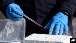 ARCHIVO - Un oficial antinarcóticos realiza un análisis químico para confirmar la pureza de un bloque de cocaína, en Cayambe, Ecuador, el viernes 3 de marzo de 2023. 