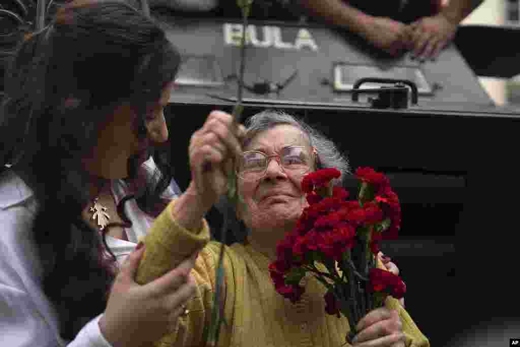 Celeste Caeiro, 90, holds a bunch of red carnations, in Lisbon, during the reenactment of troop movements of 50 years ago, part of anniversary celebrations of the Carnation Revolution.