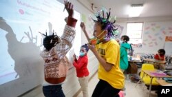 Niambi Cameron, 9, of Decatur, Ga., right, celebrates with classmates after answering a question during a math lesson at the Kilombo Academic and Cultural Institute, March 28, 2023, in Decatur, Ga. 