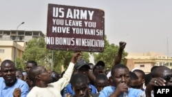 Para pengunjuk rasa bereaksi ketika seorang pria mengangkat tanda yang menuntut tentara AS meninggalkan Niger tanpa negosiasi saat demonstrasi di Niamey, pada 13 April 2024. (Foto: AFP) 