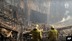 FILE - In this photo taken from video released by the Investigative Committee of Russia on March 23, 2024, firefighters work in the burned concert hall after an attack on the building of the Crocus City Hall in Moscow. The attack left 145 dead.