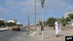 Un piéton passe devant un feu de signalisation brisé dans une rue de Dakar le 3 juin 2023, suite aux violences meurtrières dans la capitale sénégalaise (Photo by Seyllou / AFP)