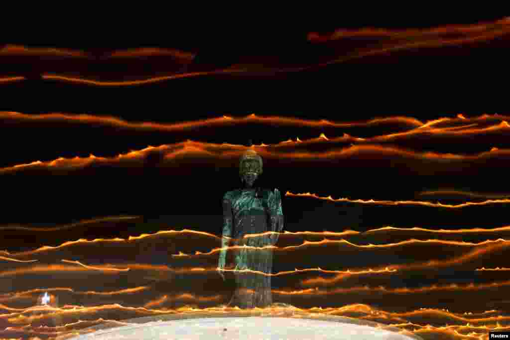 People walk with candle lights around a large Buddha statue during a ceremony commemorating Asalha Puja Day, an annual celebration marking the beginning of Triple Gem at a temple in Nakhon Pathom province on the outskirts of Bangkok, Thailand, July 20, 2024. 