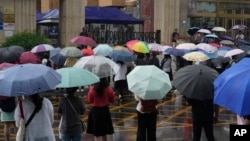 資料照片：家長和老師們冒雨在北京一所學校外等候正在參加一年一度的全國高考的考生們。 (2024年6月7日)