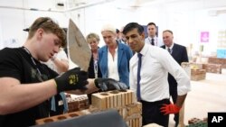 Perdana Menteri Inggris Rishi Sunak (kanan) berkunjung ke sebuah bengkel pengolahan tanah liat di Cannock College, di Cannock, Inggris, pada 24 Mei 2024. Kunjungan tersebut merupakan bagian dari kampanye Sunak dan Partai Konservatif. (Foto: Henry Nicholls/Pool via AP)
