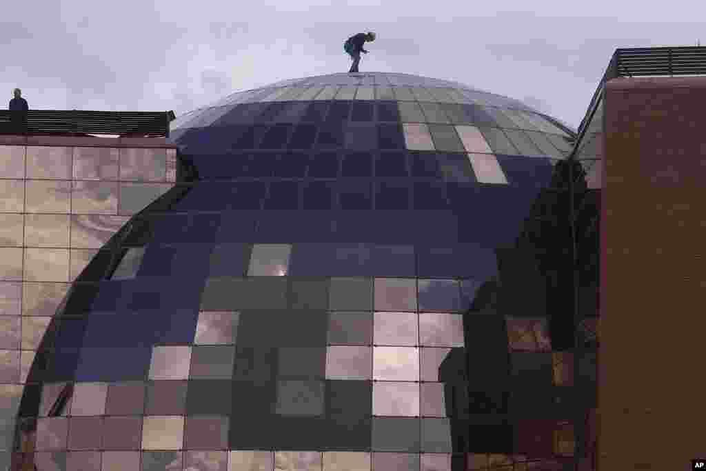 A worker stands on the domed roof of an office block in Madrid, Spain.