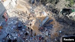 Palestinians inspect the site of an Israeli strike on a house in Rafah, in the southern Gaza Strip, May 8, 2024. 