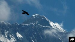 FILE - A bird flies against the backdrop of Mount Everest, as seen from Namche Bajar, Solukhumbu district, Nepal, May 27, 2019. A Kenyan climber attempting to scale the world’s highest mountain has been found dead near the summit.