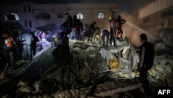 Firefighters and civilians gather at the rubble of a building following Israeli bombardment in Rafah, in the southern Gaza Strip, on Dec. 18, 2023, amid continuing battles between Israel and the Palestinian militant group Hamas.