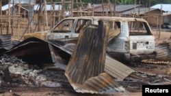Sebuah kendaraan yang terbakar berada di antara puing-puing bangunan di sebuah pasar menyusul serangan yang dilakukan Pasukan Demokratik Sekutu (ADF) yang berafiliasi dengan ISIS di desa Masala, provinsi Beni, Kongo, pada 9 Juni 2024. (Foto: Reuters/Gradel Muyisa Mumbere)