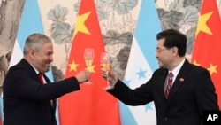 FILE - Honduras Foreign Minister Eduardo Enrique Reina Garcia, left, and Chinese Foreign Minister Qin Gang, raise a toast following the establishment of diplomatic relations between the two countries, at a ceremony in the Diaoyutai State Guesthouse in Beijing, March 26, 2023. 