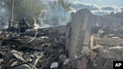 In this photo provided by the Ukrainian Presidential Press Office, firefighters work to extinguish a fire after the deadly Russian rocket attack that killed more than 40 people in the village of Hroza near Kharkiv, Ukraine, Oct. 5, 2023.