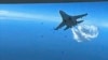 This photo taken from video released March 16, 2023, shows a Russian Su-27 approaching the back of the MQ-9 drone and beginning to release fuel as it passes, over the Black Sea, the Pentagon said. 