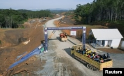 Para pekerja mengendarai truk memasuki kawasan inti pemerintahan pembangunan ibu kota baru Indonesia yang dikenal dengan Ibu Kota Negara Nusantara (IKN), di Sepaku, Kalimantan Timur, 8 Maret 2023. (Foto: Reuters)