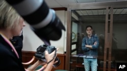 Reporter Wall Street Journal Evan Gershkovich berdiri di dalam sangkar kaca saat fotografer memotretnya di ruang sidang Pengadilan Kota Moskow, di Moskow, Rusia, 18 April 2023. Seorang wartawan Rusia menceritakan saat dia diracun Pemerintah Rusia. (Foto: AP)