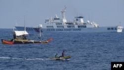 2024年5月16日，一艘中國海警船在南中國海有爭議的海域監視菲律賓漁民的木船。 
