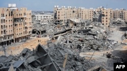 Raseljeni Palestinci hodaju između ruševina stambenih zgrada uništenih u izraelskim bombadovanima, u oblasti Hamad, u Kan Junisu, u južnoj Gazi, 14. marta 2024.