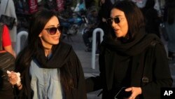 Women talk as they walk around Tajrish commercial district without wearing their mandatory Islamic headscarves in northern Tehran, Iran, April 29, 2023.