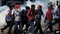 Opposition party members run for cover from police firing tear gas during a protest rally in Colombo, Sri Lanka, Feb. 26, 2023.