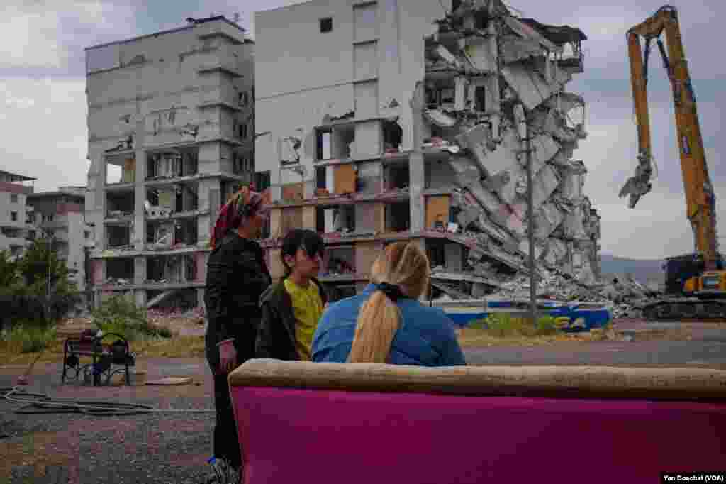 A family watches their heavily damaged building be demolished three months after they evacuated during the earthquake that killed more than 50,000 people. “I left even without my shoes,” says Sema, 27, in Nurdagi, Turkey, May, 11, 2023.
