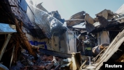 Seorang petugas pemadam kebakaran bekerja di dalam gedung Universitas Ekonomi dan Perdagangan yang habis terbakar di Donetsk, Ukraina yang dikuasai Rusia, 6 Agustus 2023. (Foto: Reuters)