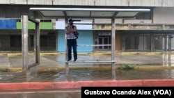 Un hombre se encarama sobre una banca en una parada del transporte en Maracaibo, Zulia, durante un chubasco, el 2 de junio de 2023. Las autoridades esperan fuertes lluvias en el norte de Venezuela, especialmente en los estados Zulia y Falcón, por el paso de Bret por el Caribe.
