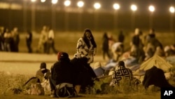 Migrants wait in the cold at a gate in the border fence after crossing from Ciudad Juarez, Mexico, into El Paso, Texas, in the early hours of May 11, 2023. (AP Photo/Andres Leighton)