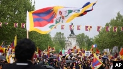 Seorang pengunjuk rasa mengibarkan bendera Tibet saat demonstrasi Minggu, 5 Mei 2024 di Paris. Presiden Prancis Emmanuel Macron menyambut Presiden China Xi Jinping untuk kunjungan kenegaraan dua hari di Prancis, Senin 6 Mei 2024. (AP/ Thomas Padilla)