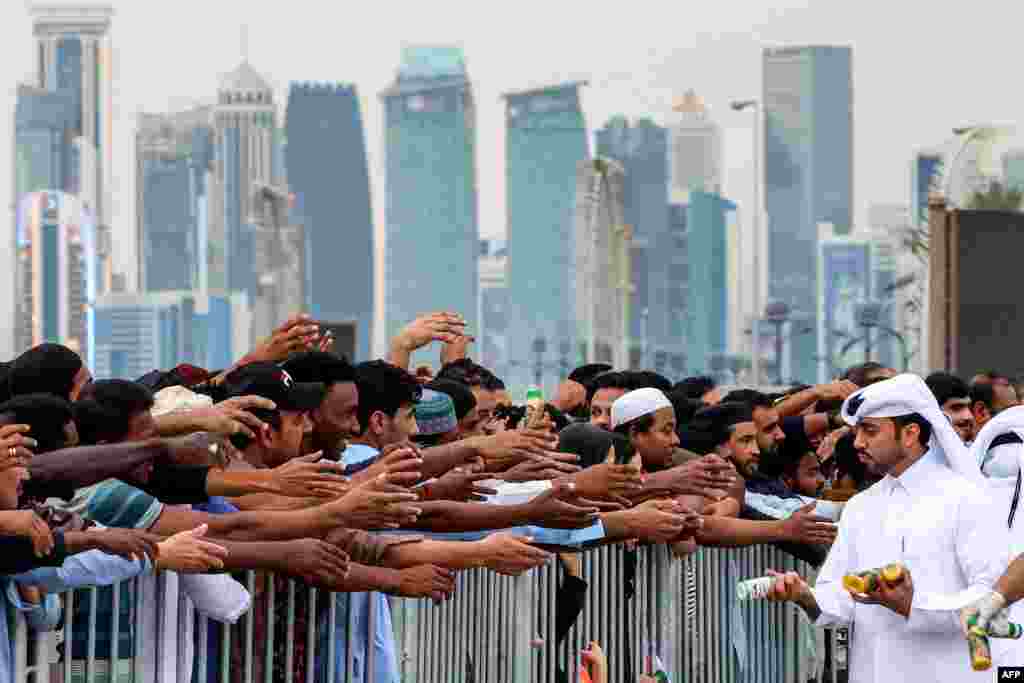 Volunteers distribute Ramadan meals to people on the last day of the Muslim holy month, at Souq Waqif Traditional Market in Doha, Qatar.