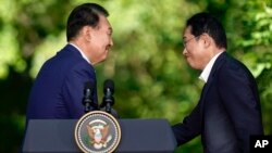 윤석열 한국 대통령과 기시다 후미오 일본 총리가 지난달 18일 미국 캠프 데이비드에서 열린 미한일 정상회담 기자회견장에서 악수하고 있다.