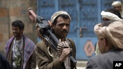 ARCHIVO - Un miembro armado de una tribu leal al jeque Sadeq al-Ahmar, jefe de la poderosa tribu Hashid, lleva su arma al hombro mientras vigila una calle junto a la casa de al-Ahmar en Sanaa, Yemen, el jueves 16 de junio de 2011.