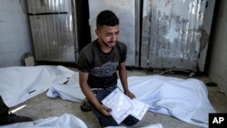 Yon Palestinyen pote dey pou 2 marasa ki te gen 4 jou selman e ki mouri nan bonbadman Izrayel fe nan Gaza, 13 Out, 2024.
