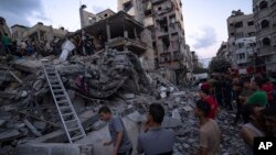 Palestinyen yo chache moun ki blese nan dekonb yon bilding rezidansyel ki detwi pandan yon atak ayeryen Israelyen, Madi 10 Oktob, 2023.