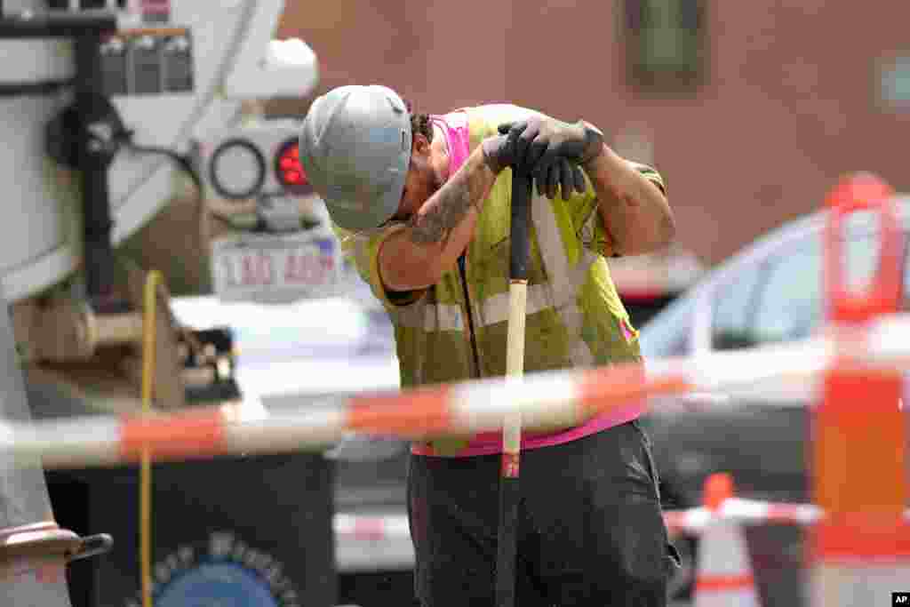 A worker wipes his face while working in temperatures above 90° F (32° C) at a gas line work site on a street in Boston, Massachusetts.