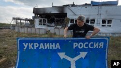Ukrainian historian Yuri Savchuk, head of the Kyiv-based Ukrainian WWII history museum, carries a road sign in Sudzha, in Russia's Kursk region, Aug. 16, 2024. The image was approved by the Ukrainian Defense Ministry before publication. 